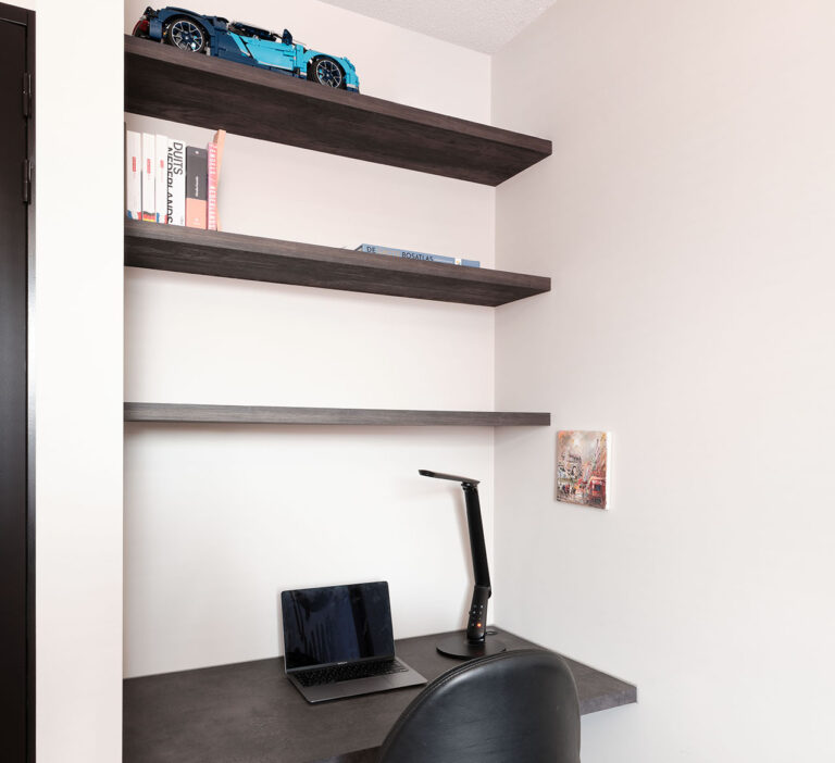 Compacte werkplek met een stijlvolle bureaustoel, laptop en decoratieve planken.