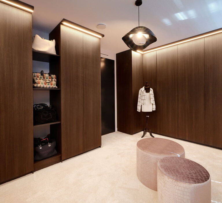 Luxe walk-in closet met stijlvolle verlichting, opbergplanken en comfortabele zittingen.