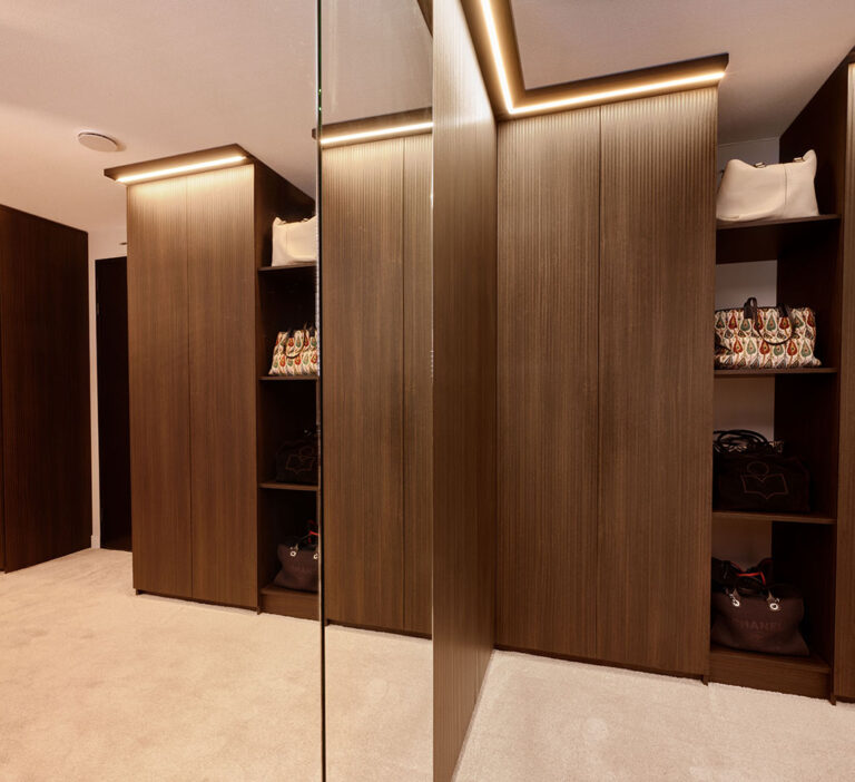 Ruime en luxe walk-in closet met sfeervolle verlichting en op maat gemaakte opbergplanken.