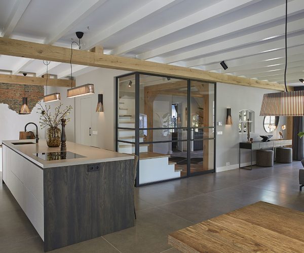 Oosteind 113 Keuken met centraal eiland, houten balken en glazen afscheiding naar hal.